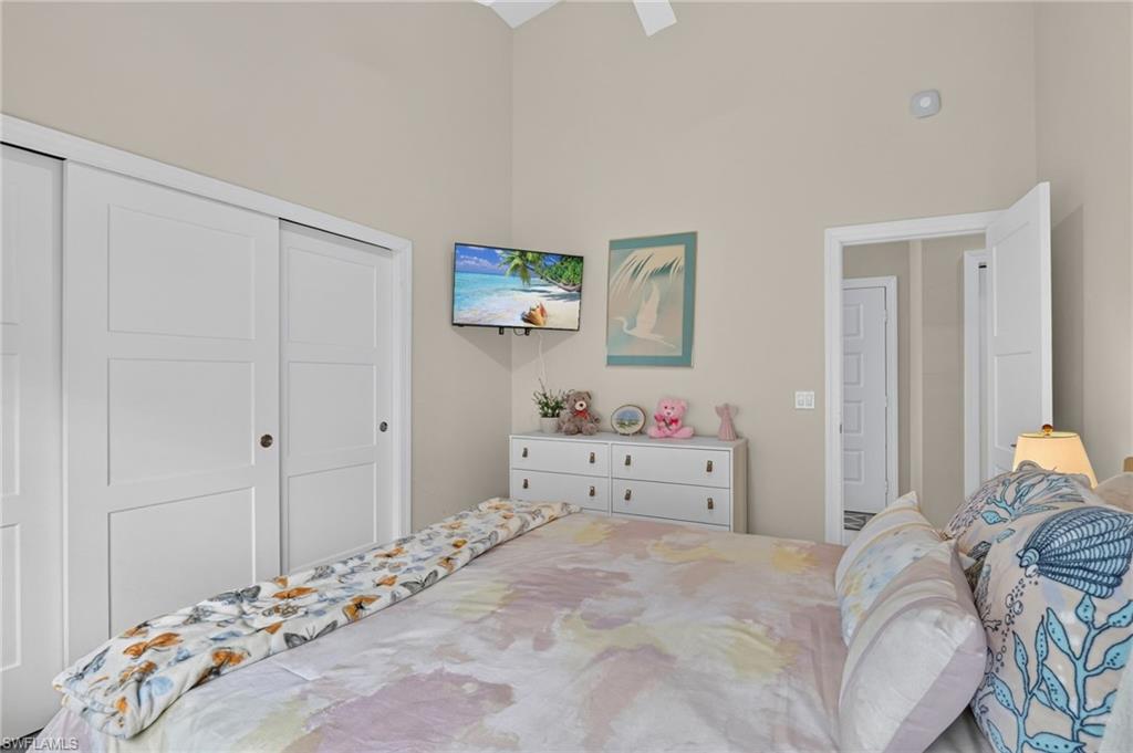 Vaulted ceiling with a ceiling fan, white paneled sliding closet doors, and recessed lighting
