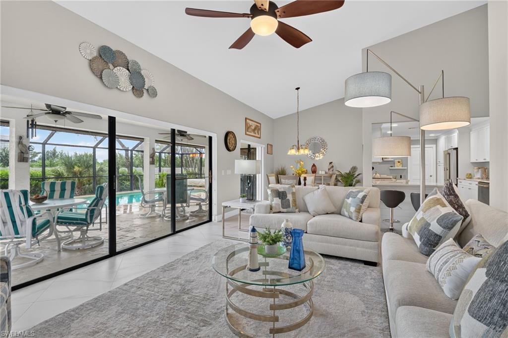 Vaulted ceilings highlight an open living area featuring tile flooring and a ceiling fan