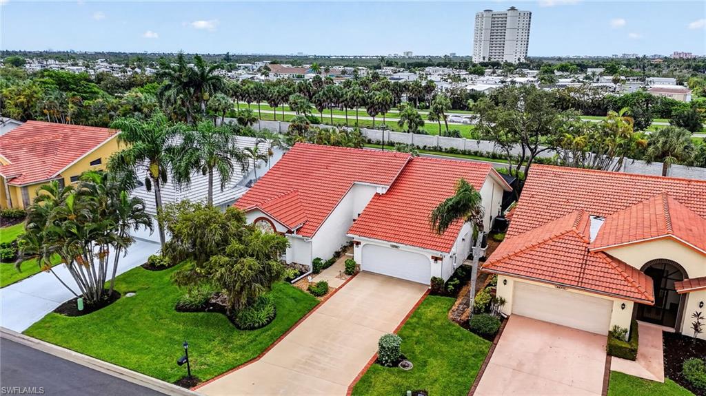 Residences featuring terracotta tile roofing, mature palm trees, established landscaping, and paved driveways