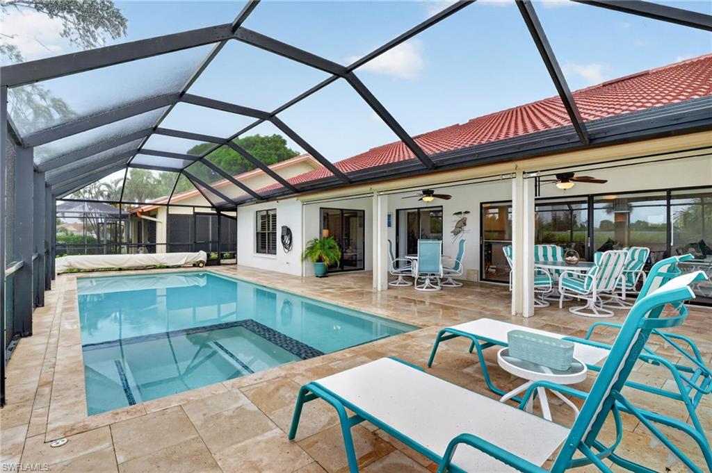Screened pool enclosure featuring a rectangular swimming pool with integrated spa and a textured tile surround