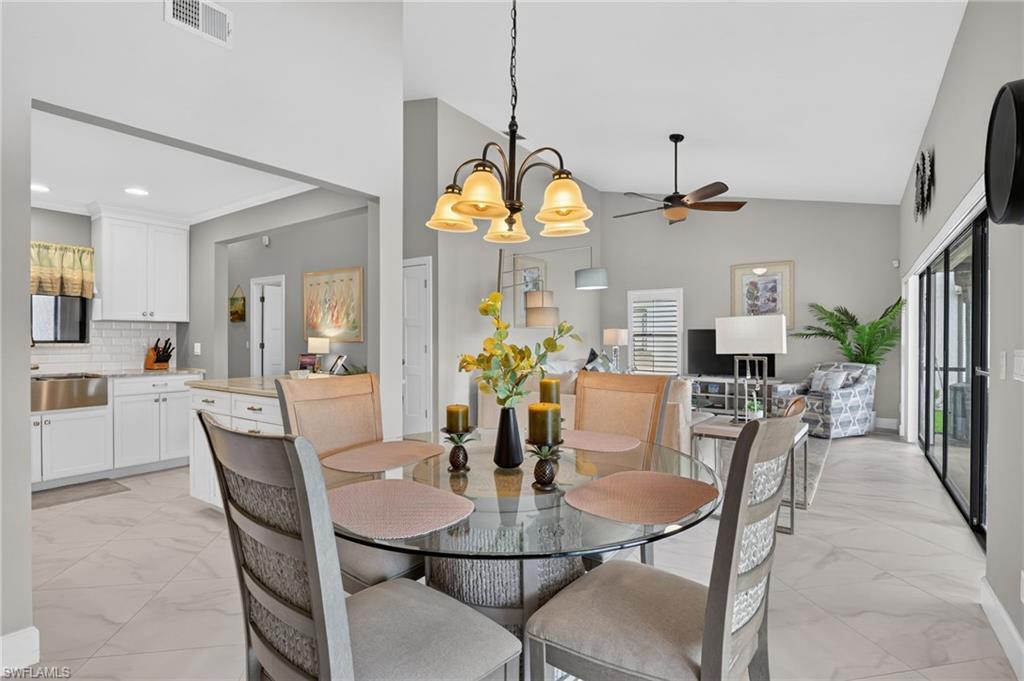 Open-concept living space featuring light-toned large format tile flooring and vaulted ceilings