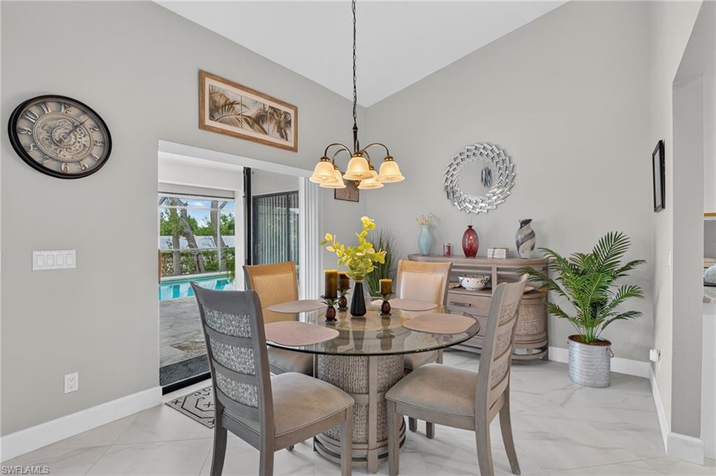 Vaulted ceiling with a chandelier, tile flooring, built-in buffet, and sliding glass doors opening to a screened pool area