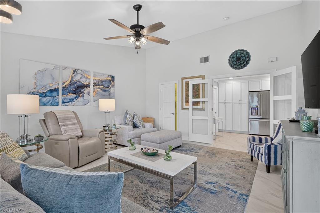 Spacious living area featuring high ceilings, a ceiling fan with integrated lighting, and light-toned flooring