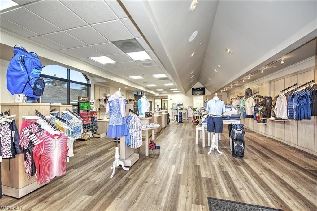 Spacious retail interior featuring wood-finish flooring, ample natural light from large windows, and varied ceiling heights including a vaulted section