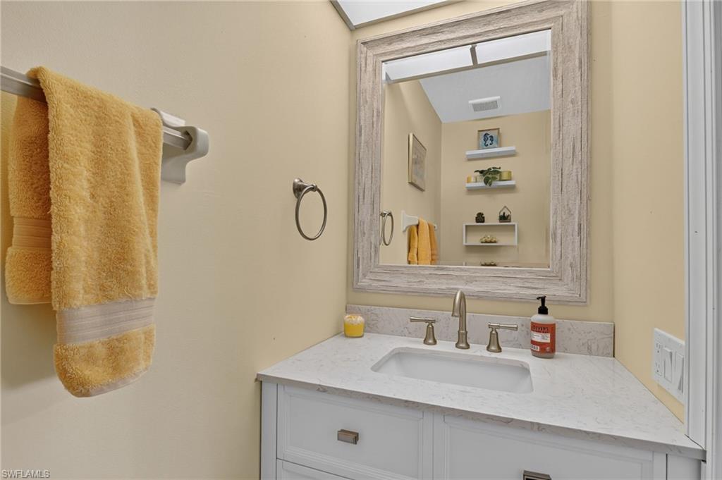 Bathroom vanity featuring a quartz countertop, integrated sink, and brushed nickel fixtures