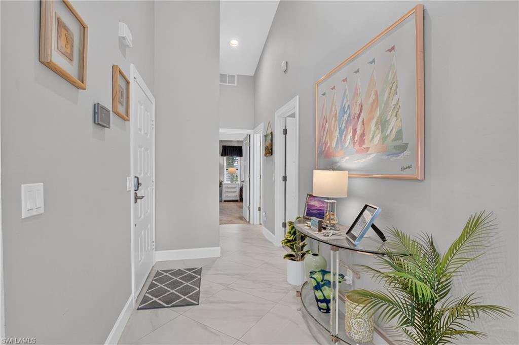 Entrance hallway featuring light gray walls, white trim, and large format tile flooring