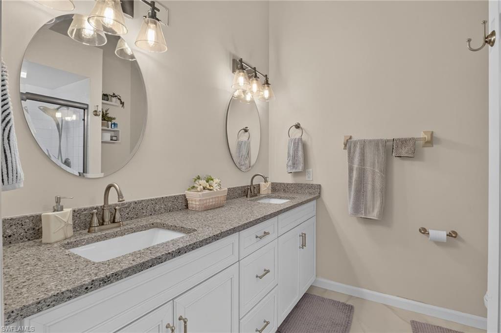 Double vanity featuring gray speckled countertops, undermount sinks, and brushed nickel faucets