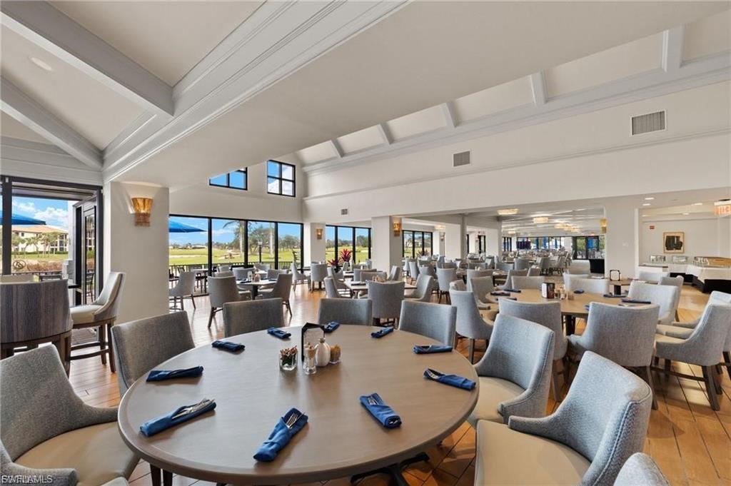 Spacious dining area featuring wood-finish flooring, large windows, recessed lighting, and high ceilings with architectural beams