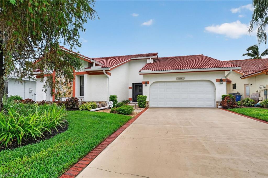 Mediterranean-style residence featuring a red tile roof, stucco exterior, and an attached two-car garage