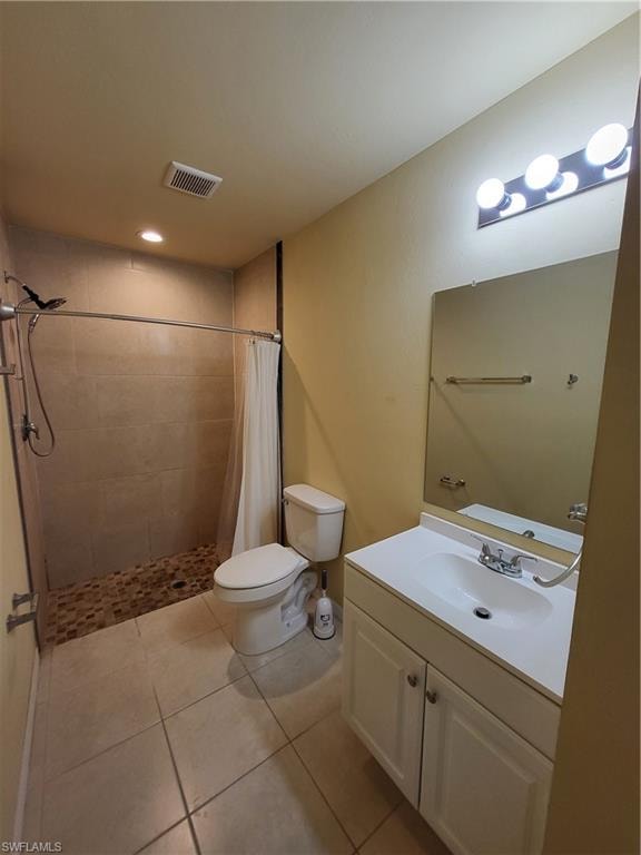 Bathroom with visible vents, toilet, a tile shower, vanity, and tile patterned floors