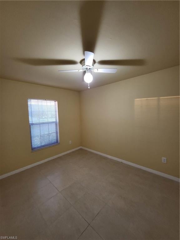 Unfurnished room featuring tile patterned flooring, a ceiling fan, and baseboards