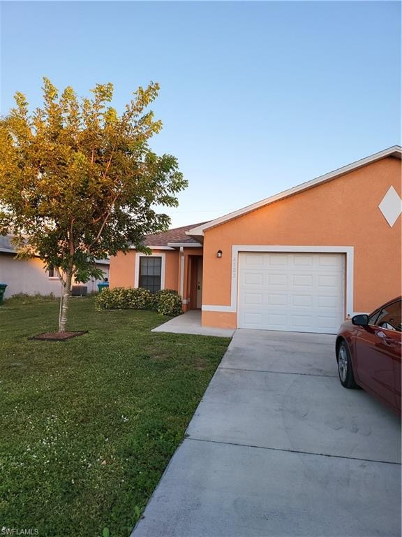 View of front of property featuring an attached garage, driveway, a front lawn, and stucco siding
