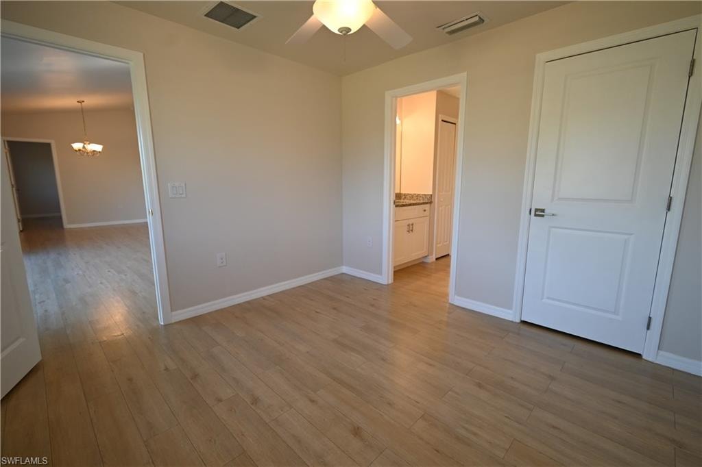 Wood-finish flooring throughout, ceiling fan with integrated lighting, two-panel interior doors, and a bathroom vanity with a light-colored countertop