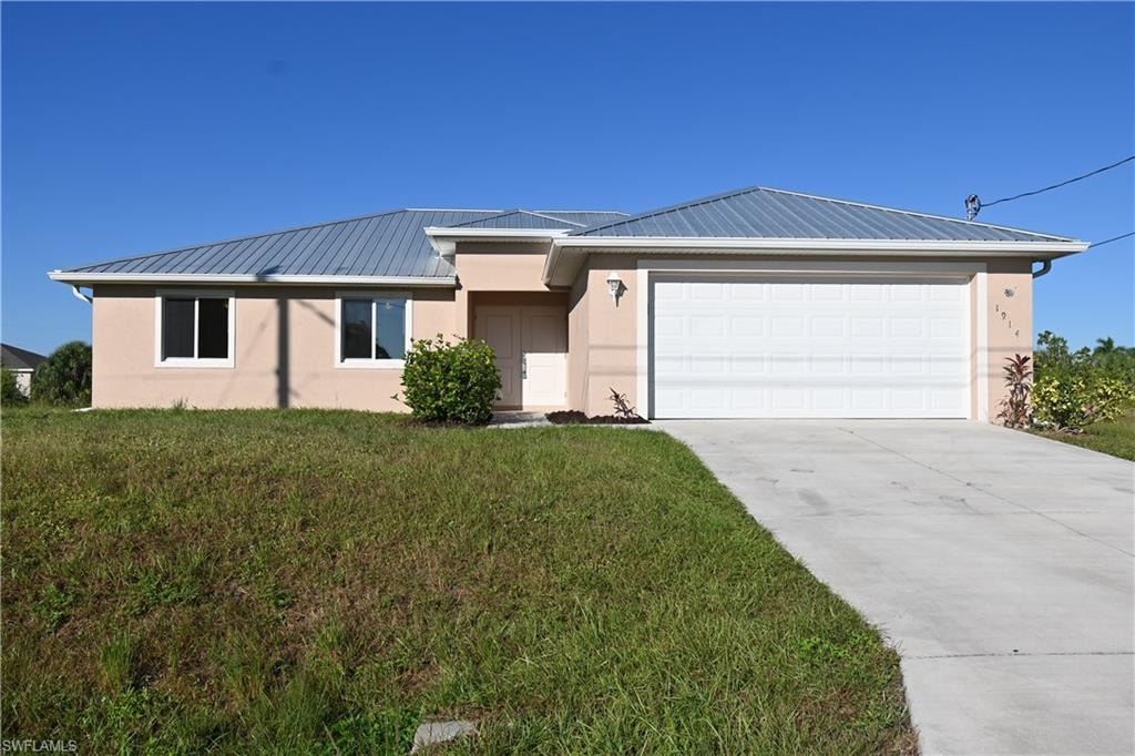 Stucco exterior with a metal roof, attached two-car garage, and concrete driveway