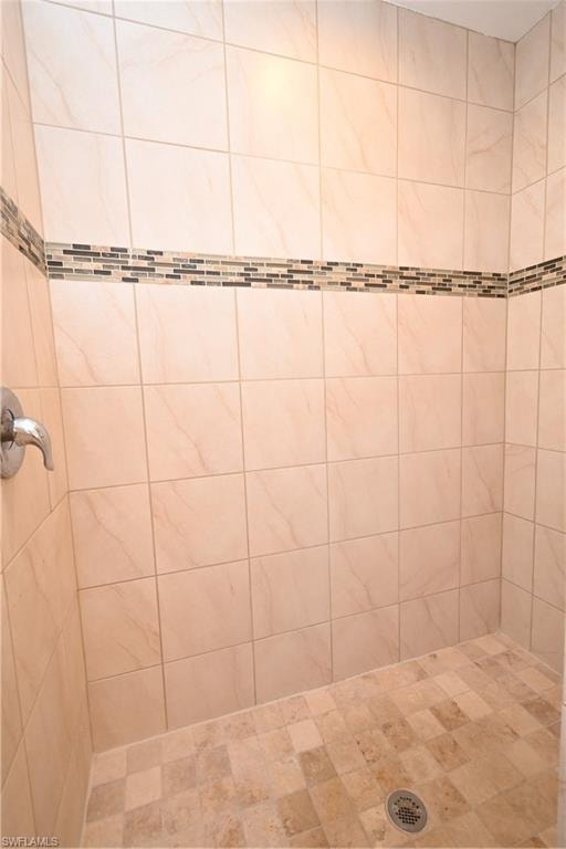 Tile shower stall with a mosaic accent band, coordinating tiled floor, and a chrome shower fixture