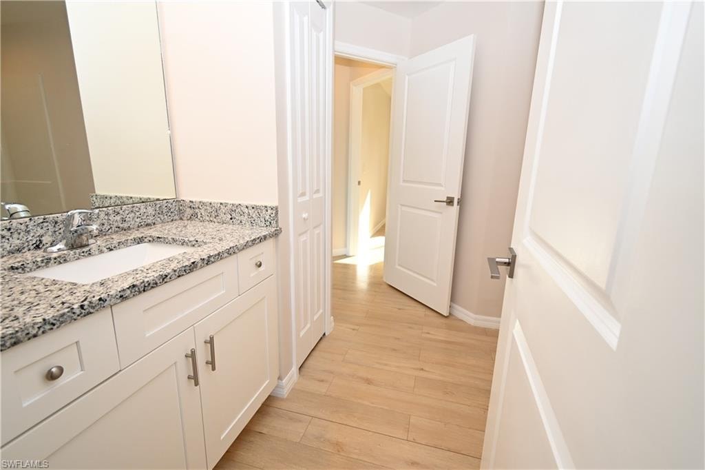 White shaker-style vanity with granite countertop and integrated sink