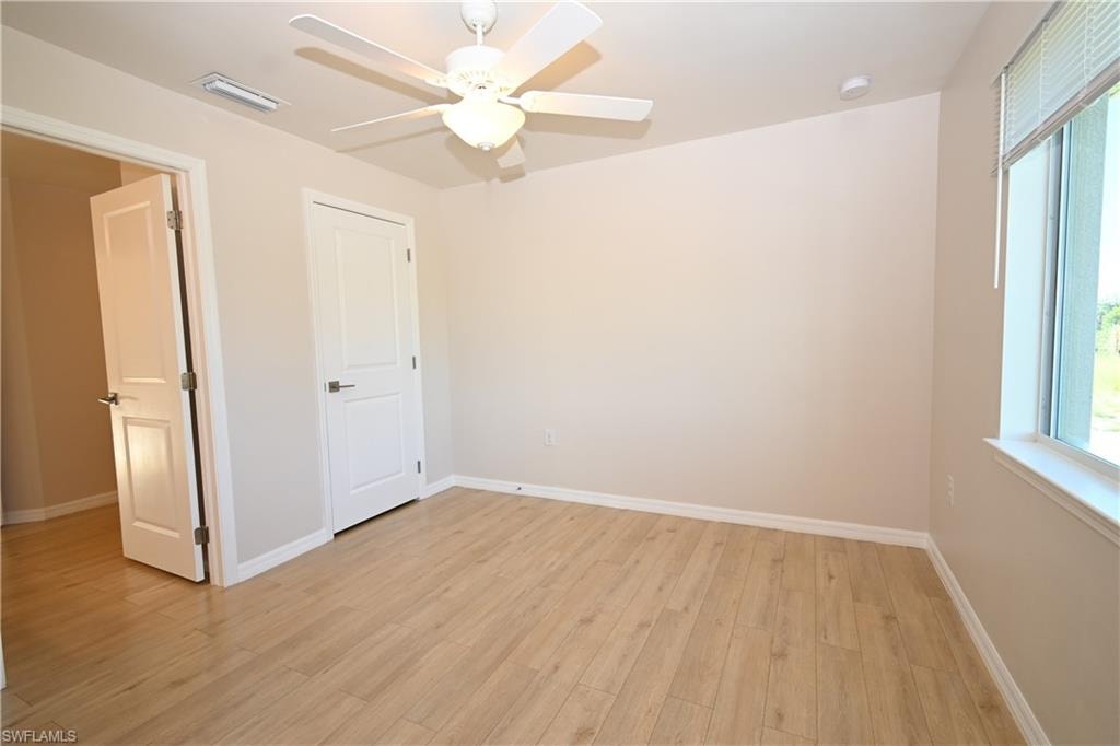 Light wood-finish flooring, recessed lighting, ceiling fan with integrated light, and a window with blinds