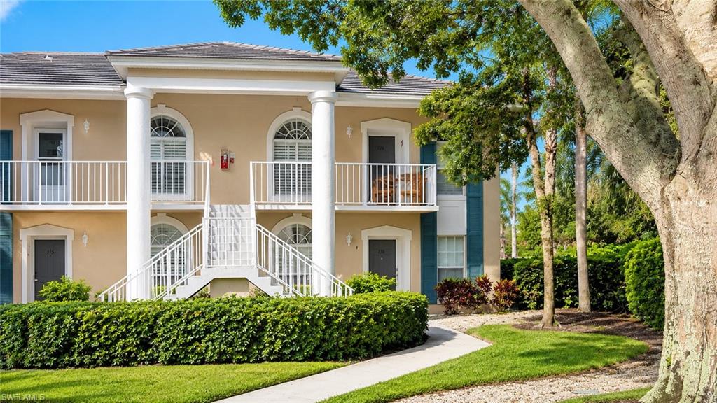 Stucco exterior with prominent white columns, arched windows, and balconies with white railings