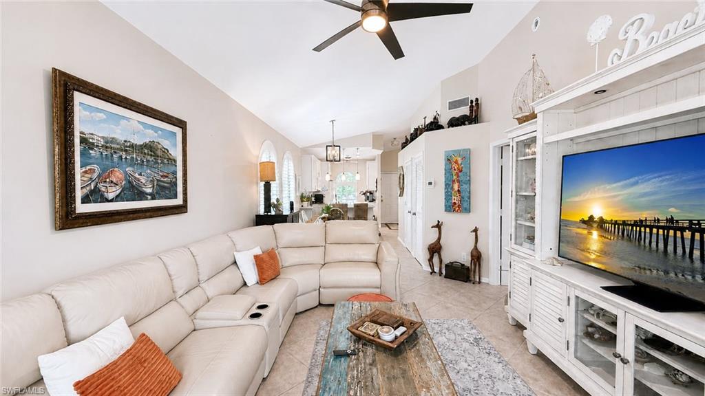 Vaulted ceiling, tiled flooring, built-in entertainment center, ceiling fan, and sliding glass doors