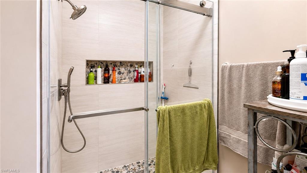Glass-enclosed shower with a brushed nickel shower head and handheld sprayer
