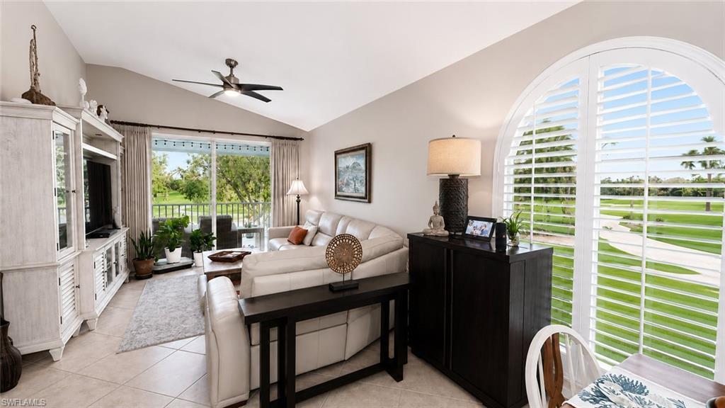 Vaulted ceilings, large sliding glass door, white built-in media console with glass-front display cabinets, and tile flooring