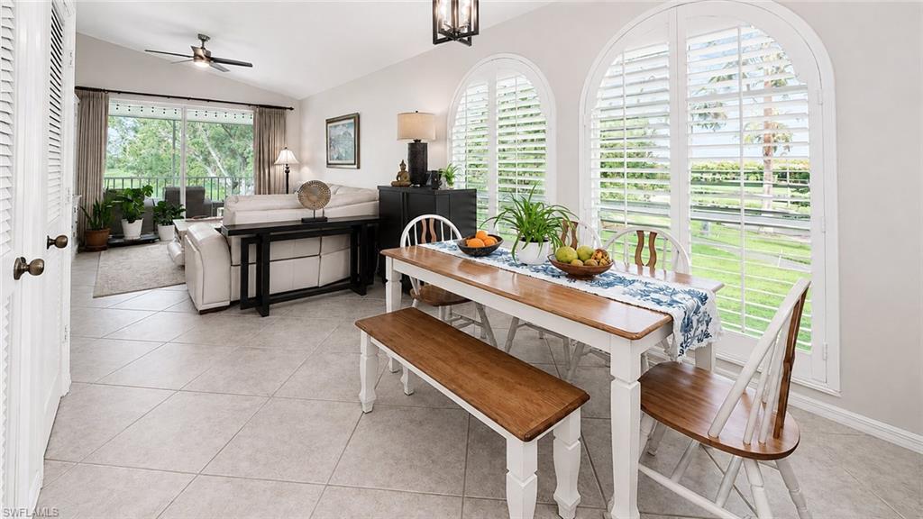 Open-concept living space featuring vaulted ceilings, tile flooring, and custom arched plantation shutters