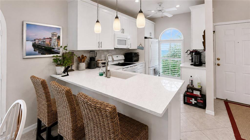 Kitchen featuring white cabinetry, light-toned countertops, a built-in microwave, and pendant lighting