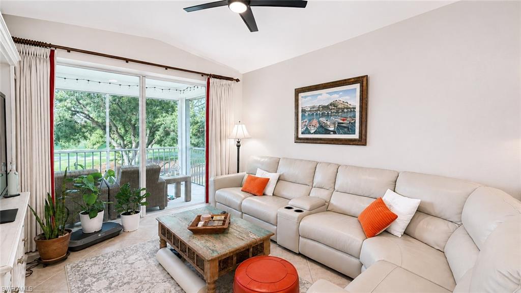Vaulted ceiling with recessed lighting, arched window accents, kitchen with white cabinetry, tile flooring, and built-in white display cabinet