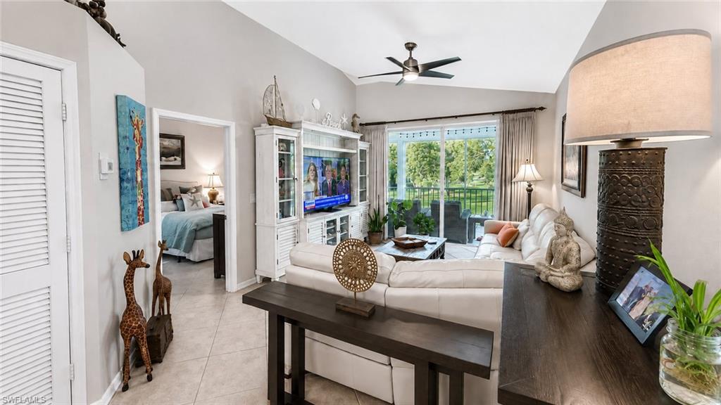 Vaulted ceiling with a ceiling fan, tile flooring, and arched window with plantation shutters