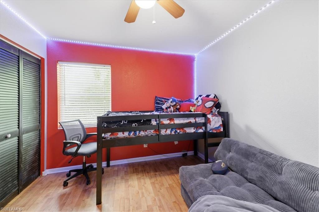 Room featuring wood-finish flooring, a ceiling fan, and a window with horizontal blinds