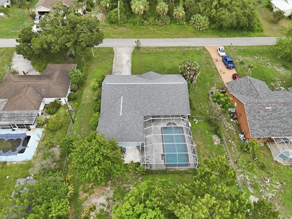 Single-story residence featuring a gray shingle roof and a screened-in swimming pool