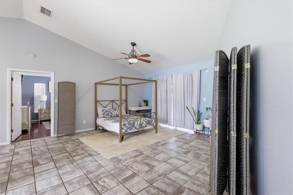 Vaulted ceiling with an overhead fan, large format tile flooring, and light-filtering window treatments