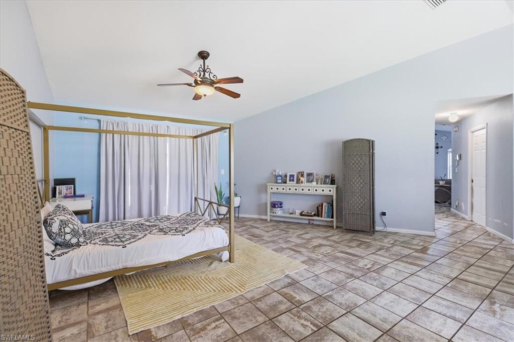 Spacious room featuring tile flooring, vaulted ceilings, and a ceiling fan with integrated lighting