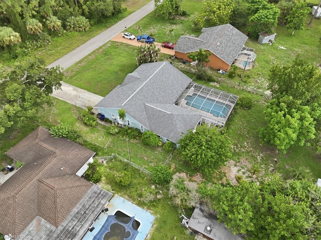 Expansive property featuring a screened-in swimming pool, mature trees, and a private driveway