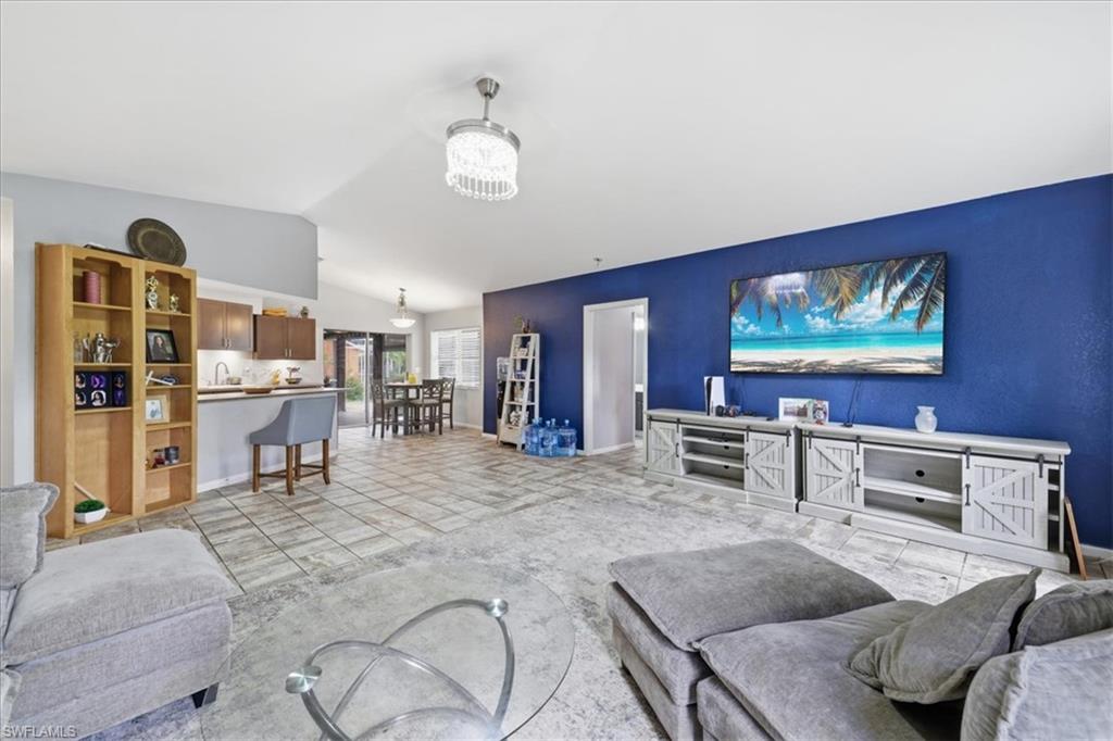 Open-concept living space featuring vaulted ceilings, tile flooring, a kitchen island with a breakfast bar, and a dedicated dining area