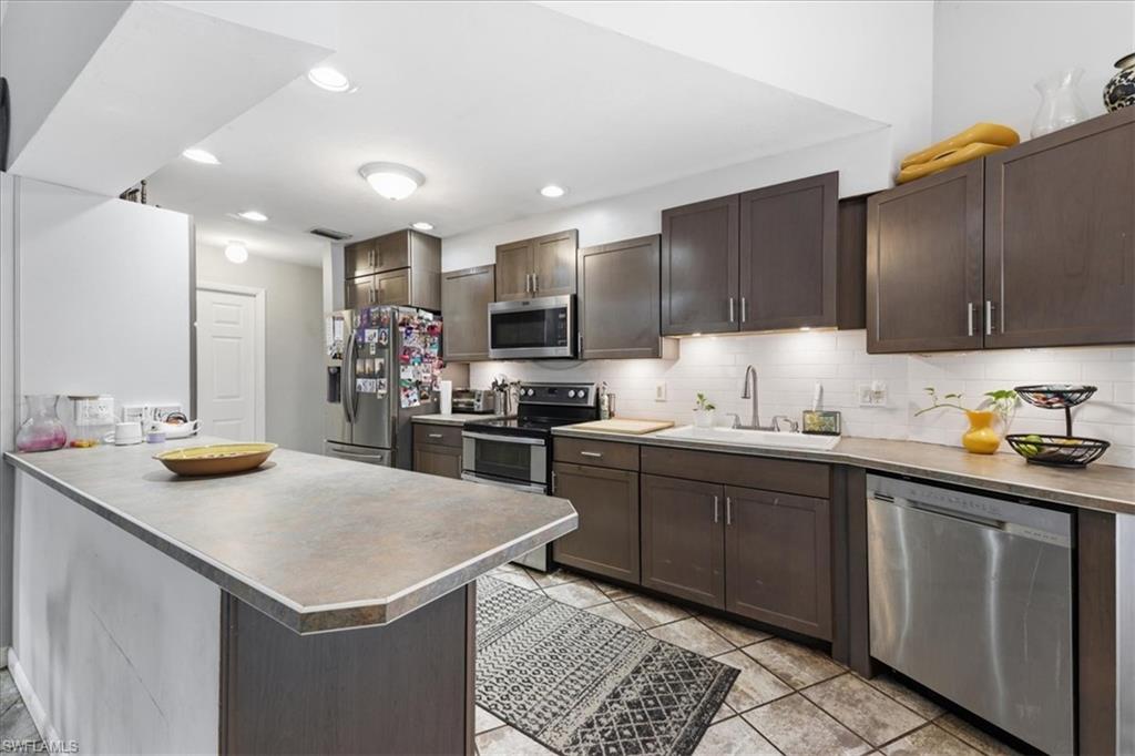 Kitchen with dark wood-finish cabinetry, solid surface countertops, and a white subway tile backsplash