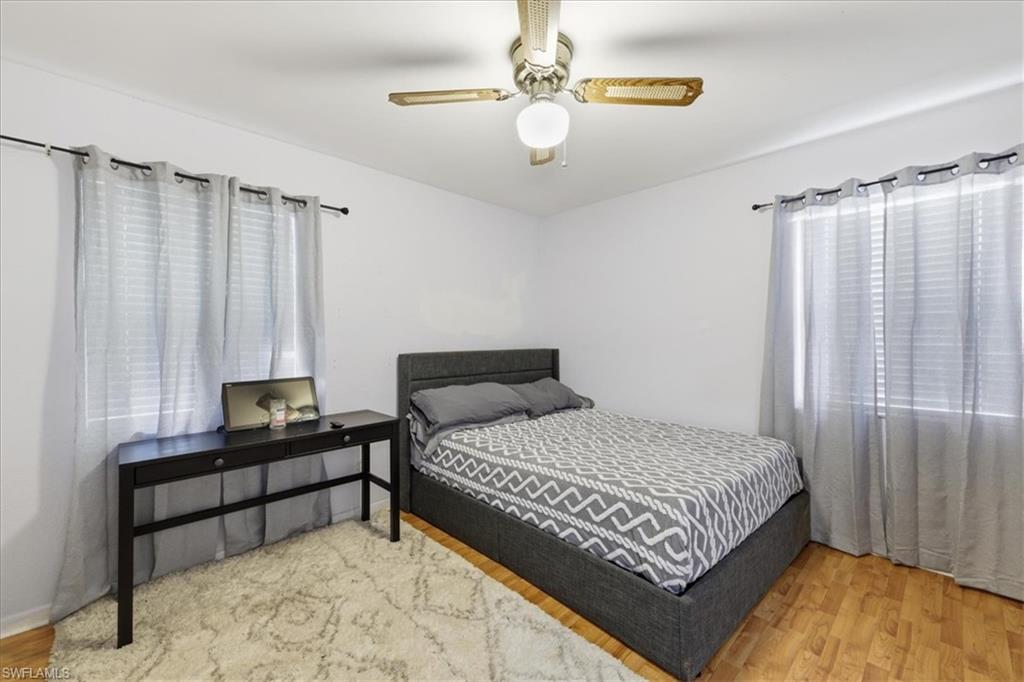 Room featuring wood-finish flooring, white walls, and two windows with blinds