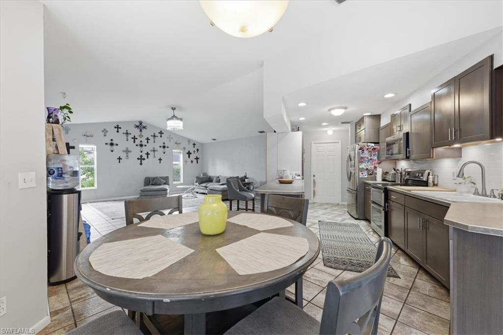 Kitchen and dining area featuring tile flooring, dark wood-finish cabinetry, stainless steel appliances, and an integrated kitchen island