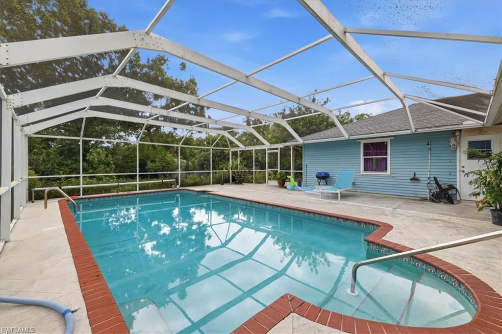 Screened-in swimming pool with a concrete deck, red brick coping, and integrated steps