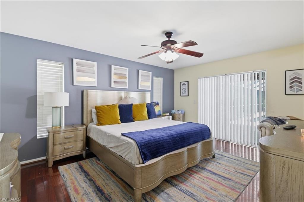 Spacious room featuring wood-finish flooring, a ceiling fan, and sliding glass doors with vertical blinds