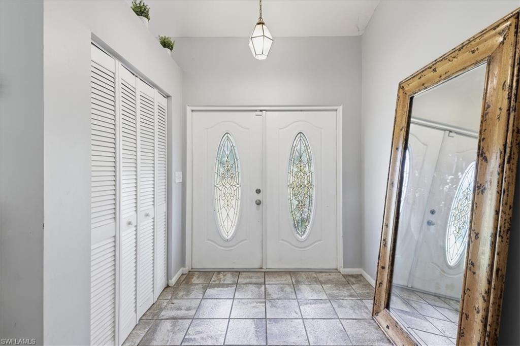 Entryway featuring double doors with decorative oval glass inserts, louvered bi-fold closet doors, and square tile flooring