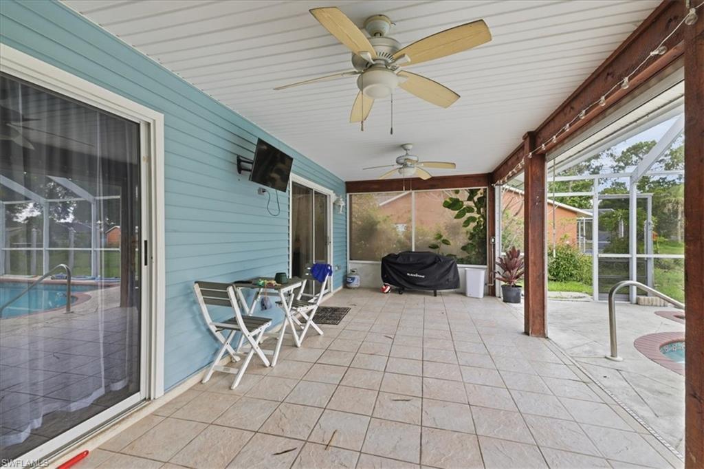 Expansive covered patio featuring tile flooring, dual ceiling fans, and screened enclosure