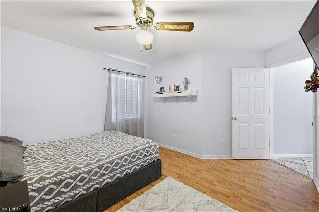 Room featuring wood-finish flooring, a ceiling fan with integrated lighting, and a window with blinds
