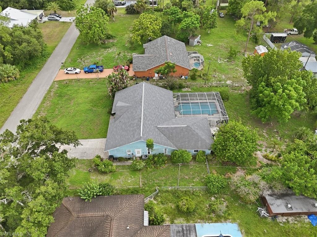 Turquoise single-story residence featuring a screened-in pool, a paved driveway, and a shingle roof