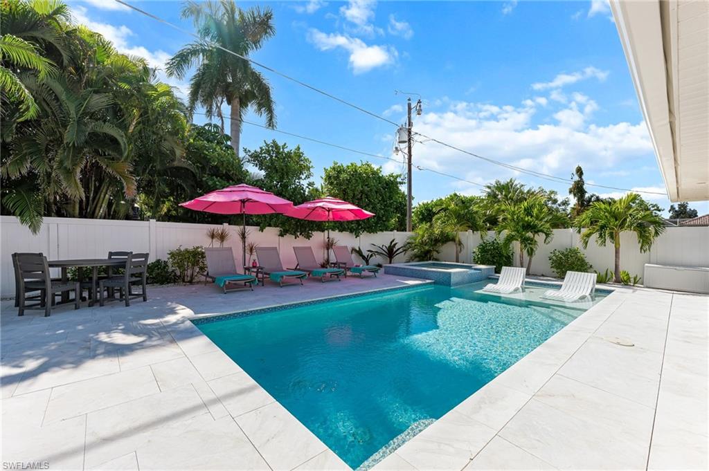 View of pool featuring a patio area, a fenced backyard, and a pool with connected hot tub