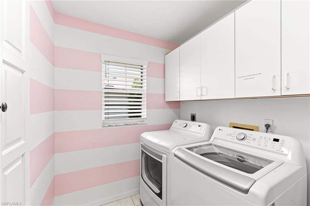 Laundry area featuring washing machine and dryer, cabinet space, and light tile patterned floors