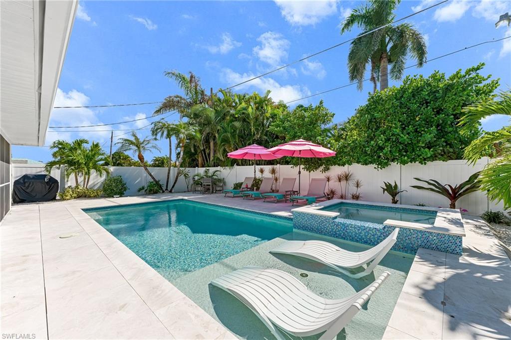 View of swimming pool with a patio area, a pool with connected hot tub, and a fenced backyard