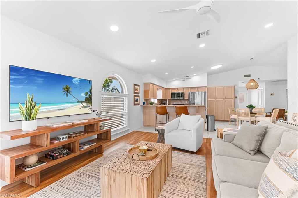 Living room featuring light wood-style floors, ceiling fan, recessed lighting, and vaulted ceiling