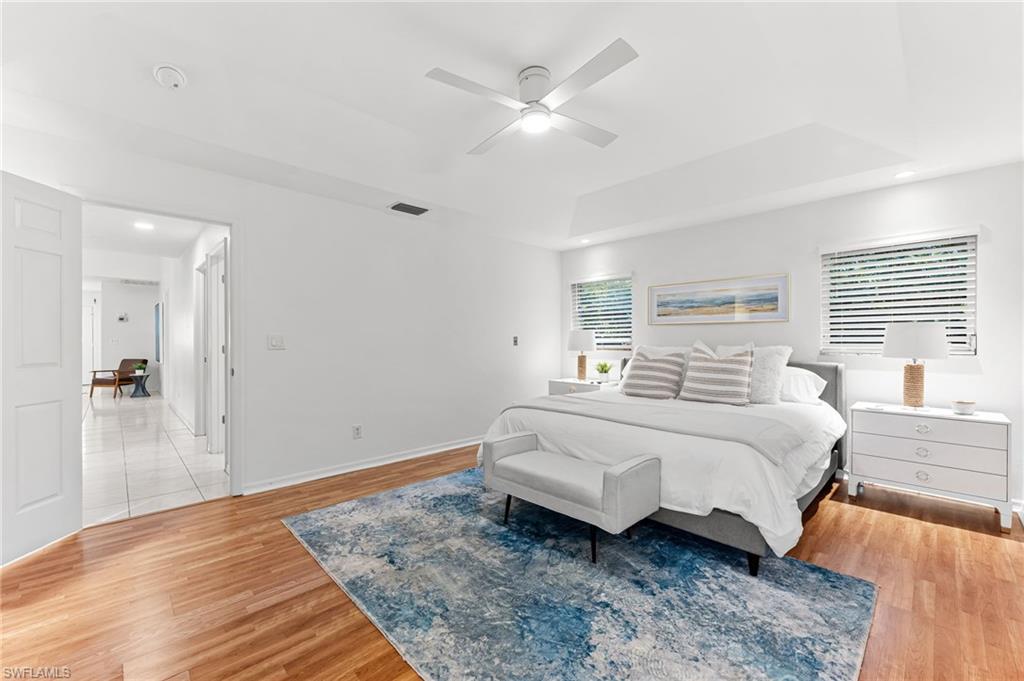 Bedroom with light wood-style flooring, a raised ceiling, a ceiling fan, and recessed lighting
