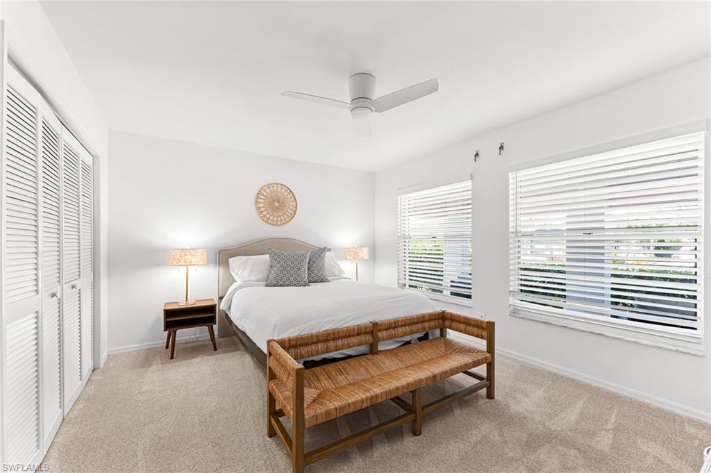 Bedroom with light carpet, ceiling fan, and a closet